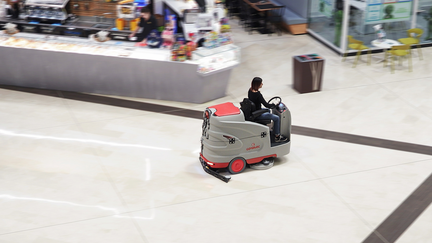 Ride-on floor scrubber operating in a shopping mall.